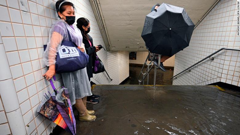 People stand inside a subway station in New York City as water runs past their feet on Wednesday, September 1.