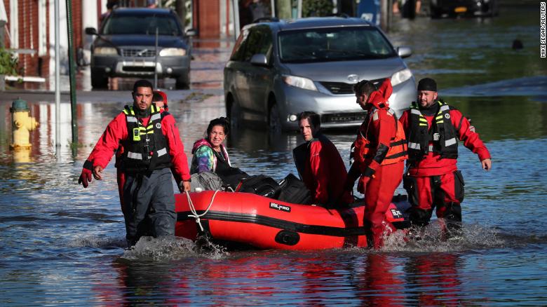 First responders pull local residents in a boat as they perform rescues in Mamaroneck, New York.