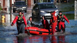 First responders pull local residents in a boat as they perform rescues in Mamaroneck, New York.