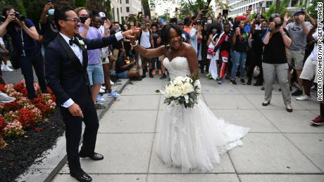 Waizeru Johnson holds her new husband&#39;s hand as she passes a group of people celebrating the Juneteenth holiday at Black Lives Matter Plaza in Washington on June 19, 2021. 