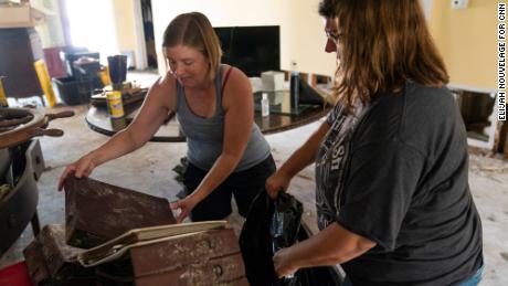 Michelle Smith, left, and her sister Cassie Falgoust throw out water-damaged family photo albums.