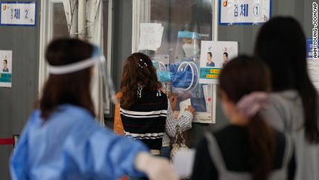 A medical worker in a booth takes a nasal sample from a woman during coronavirus testing at a makeshift testing site in Seoul, South Korea on Tuesday, September 7.