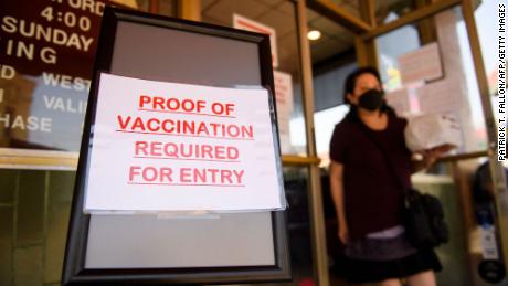 A sign stating proof of a Covid-19 vaccination is required is displayed outside of Langer&#39;s Deli in Los Angeles on August 7.