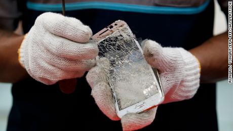 A worker dismantles a discarded mobile phone during a recycle operation at Total Environmental Solutions in Thailand in 2020.