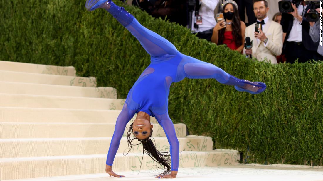 Gymnast Nia Dennis made a dramatic entrance wearing a blue Stella McCartney dress, which featured a sheer mesh skirt. As she approached the steps, she removed her skirt to reveal a crystal-embellished blue bodysuit and launched into acrobatics.
