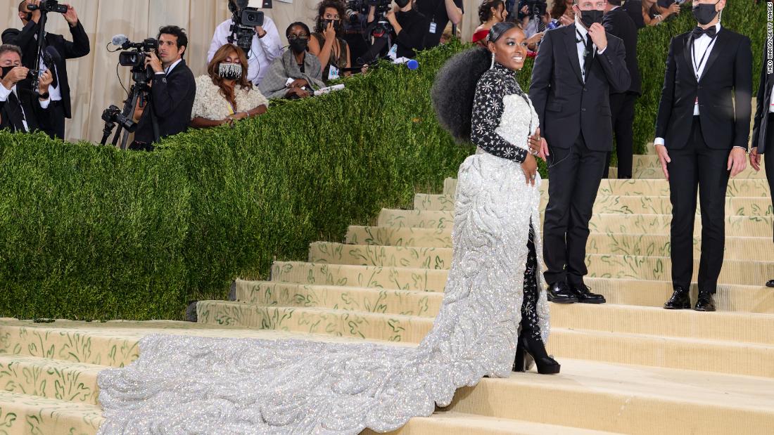 Simone Biles wore a show-stopping gown made by Area in collaboration with Athleta. Her Swarovski-embellished skirt weighed 88 pounds, according to Vogue, and required six people to assist her up the steps. On Instagram, she revealed that the skirt was detachable and hid a fringed cocktail dress -- which she then removed to unveil her final look: a black starry bodysuit.