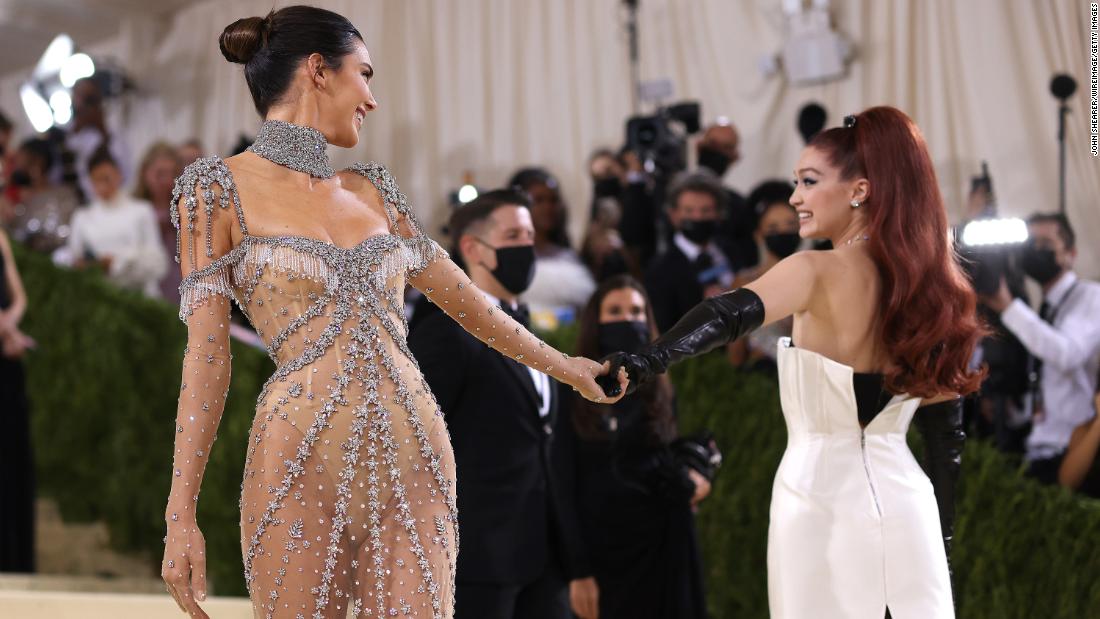 Friends Kendall Jenner and model Gigi Hadid held hands on the red carpet. Wearing her red hair in a high ponytail, the latter channeled the spirit of old Hollywood in a classic corseted white sheath dress by Prada and black evening gloves.