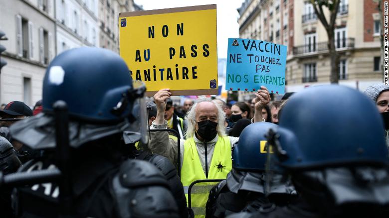 A protester holds signs reading, &quot;No to the health pass&quot; and &quot;Vaccine: keep away from our children,&quot; at a demonstration in the western Paris suburb of Neuilly-sur-Seine on August 7.