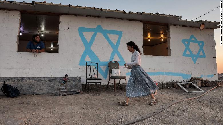 A young woman walks past a simple housing unit in the settlement of Givat Evyatar, West Bank, on July 1.