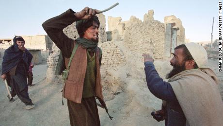 A Taliban militiaman arrests and beats a man who was allegedly found in possession of half a kilogram of opium in Kabul in November 1996.