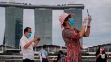 A woman wearing mask and gloves takes pictures at Singapore&#39;s Marina Bay on August 1, 2021.