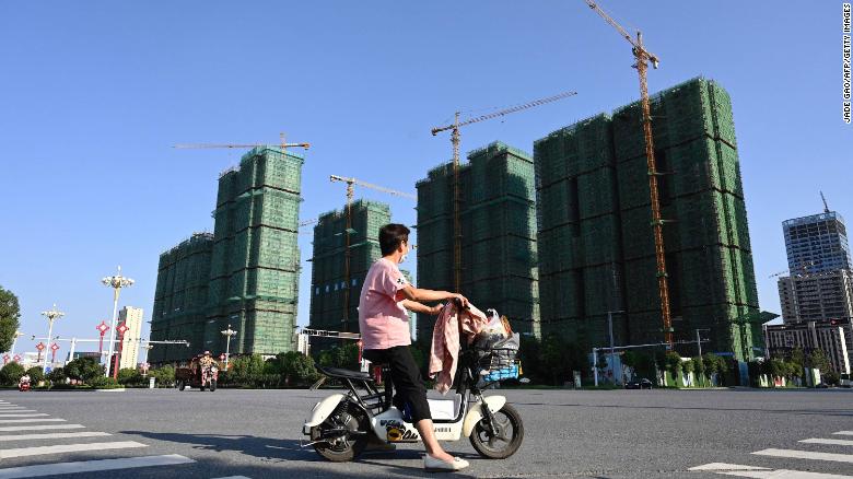 A woman riding a scooter past the construction site of an Evergrande housing complex in Zhumadian, Henan province on Sept. 14, 2021. 