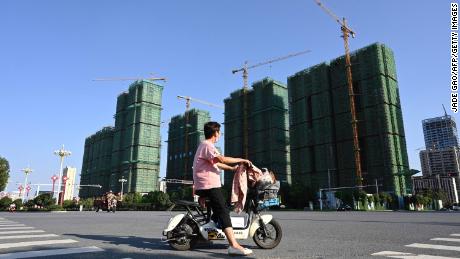 A woman riding a scooter past the building site of an Evergrande residential complex in Zhumadian, Henan Province, on September 14, 2021. 