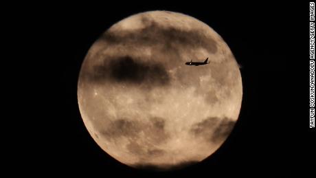 Un avión sobrevuela la luna de la cosecha mientras se eleva detrás de la Estatua de la Libertad en la ciudad de Nueva York, el 1 de octubre de 2020.