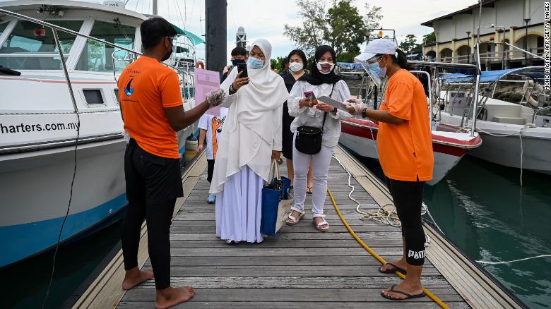 Passengers scan an app to monitor their health status before boarding a yacht in Langkawi, Malaysia, on September 17.