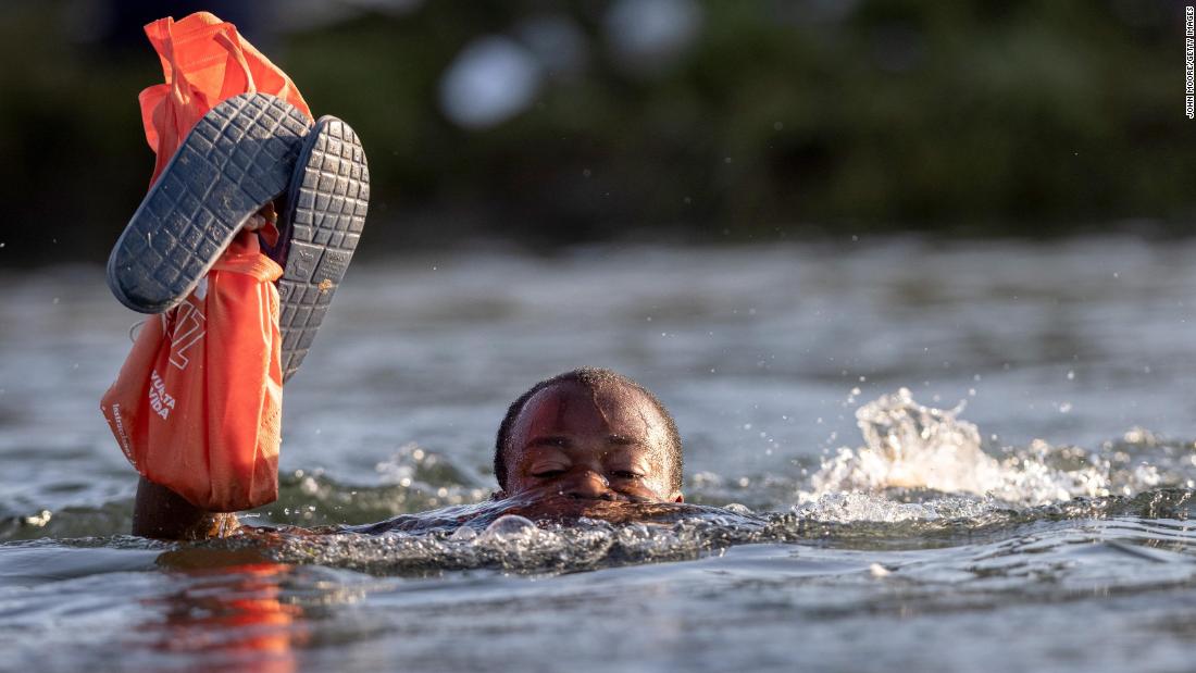 A migrant carries his belongings above water as he crosses the Rio Grande back into Mexico.