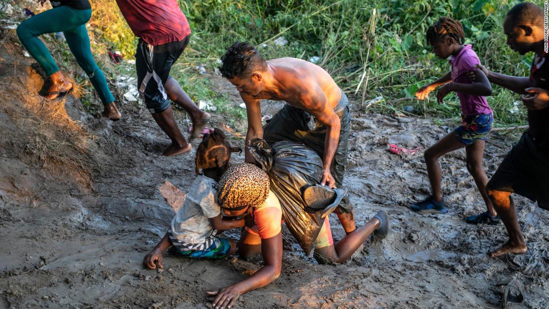 Migrants fall in the mud after wading across the Rio Grande back into Mexico on September 20.