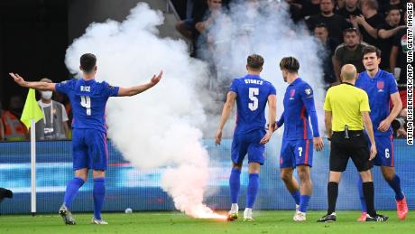 Players react as the game needs to be interrupted due to flares landing on the pitch.