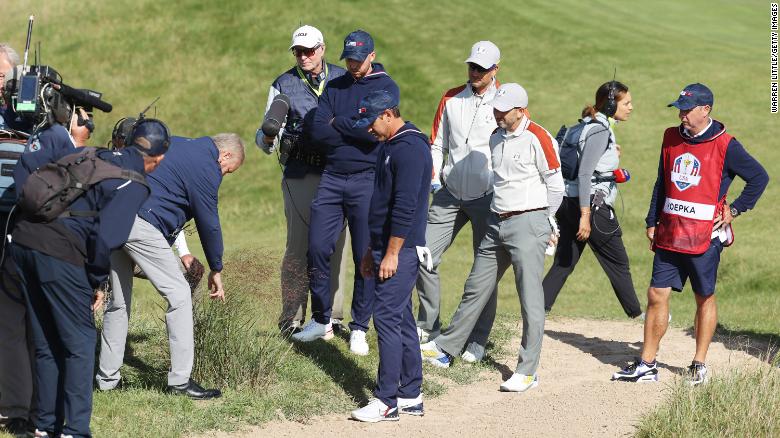 An official inspects the lie of a ball for Team US&#39; Brooks Koepka (center) and Daniel Berger on the 15th hole. The pair &lt;a href=&quot;https://www.cnn.com/2021/09/25/golf/brooks-koepka-drop-controversy-ryder-cup-spt-intl/index.html&quot; target=&quot;_blank&quot;&gt;called over two sets of officials&lt;/a&gt; to attempt to get a free drop but it was ultimately refused.