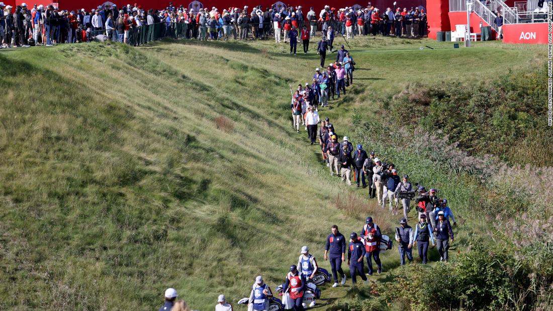 A line of people follow the foursome of Xander Schauffele and Patrick Cantlay against  Europe&#39;s Lee Westwood and Matt Fitzpatrick on the 10th hole.