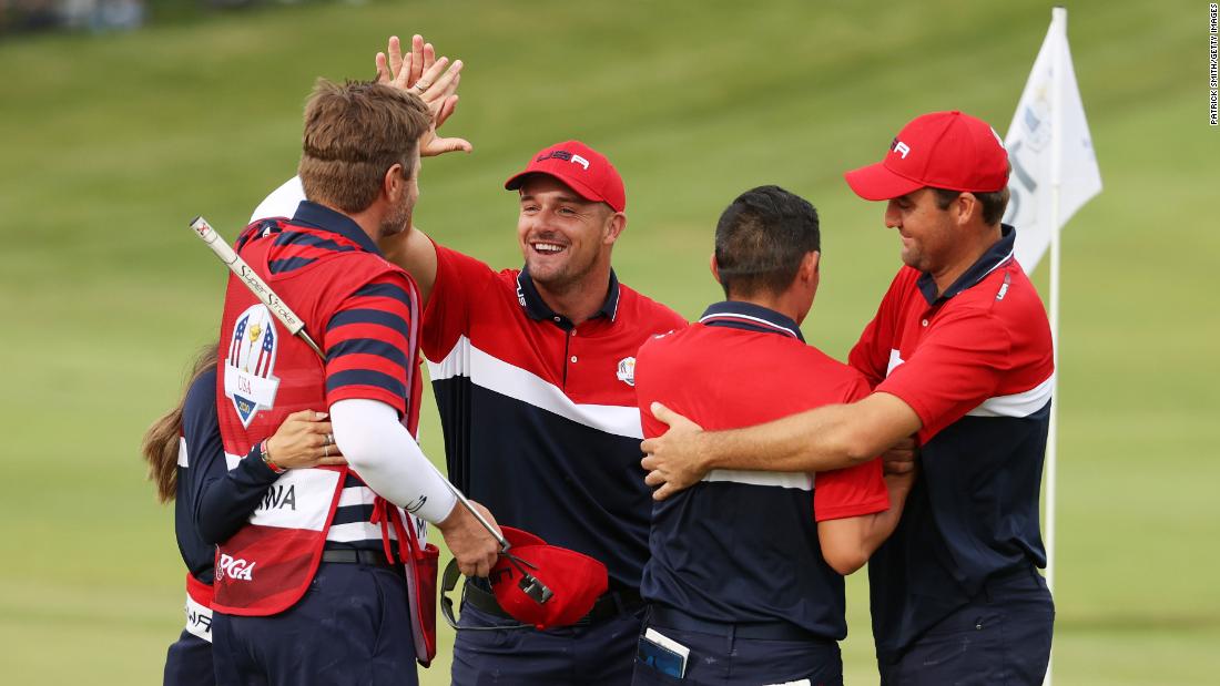 Collin Morikawa celebrates on the 18th green with Bryson DeChambeau and Scottie Scheffler after winning the half point needed to win the Ryder Cup.