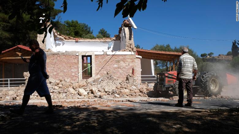 Residents pass next to a damaged Greek Orthodox chapel after a strong earthquake in Arcalochori village on the southern island of Crete, Greece, Monday, Sept. 27, 2021.