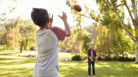 This photo shows a father and son throwing a soccer ball.