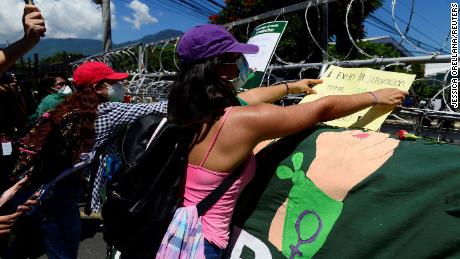 Women place placards on the fence during Tuesday&#39;s protest in El Salvador.