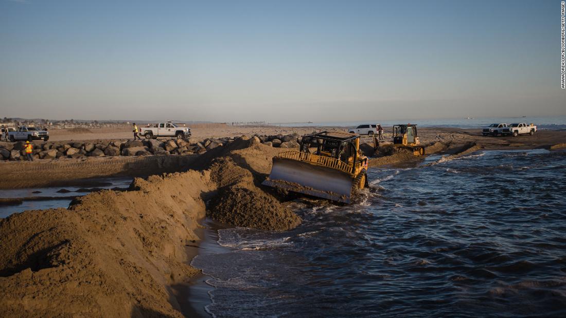 Excavators dredge sand to block some of the oil from flowing into Huntington Beach on October 3.