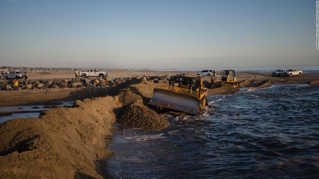 Excavators dredge sand to block some of the oil from flowing into Huntington Beach on Sunday, October 3.