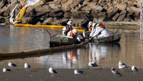 Workers in boats try to clean up floating oil near gulls in the Talbert Marsh in Newport Beach, California, on Sunday.