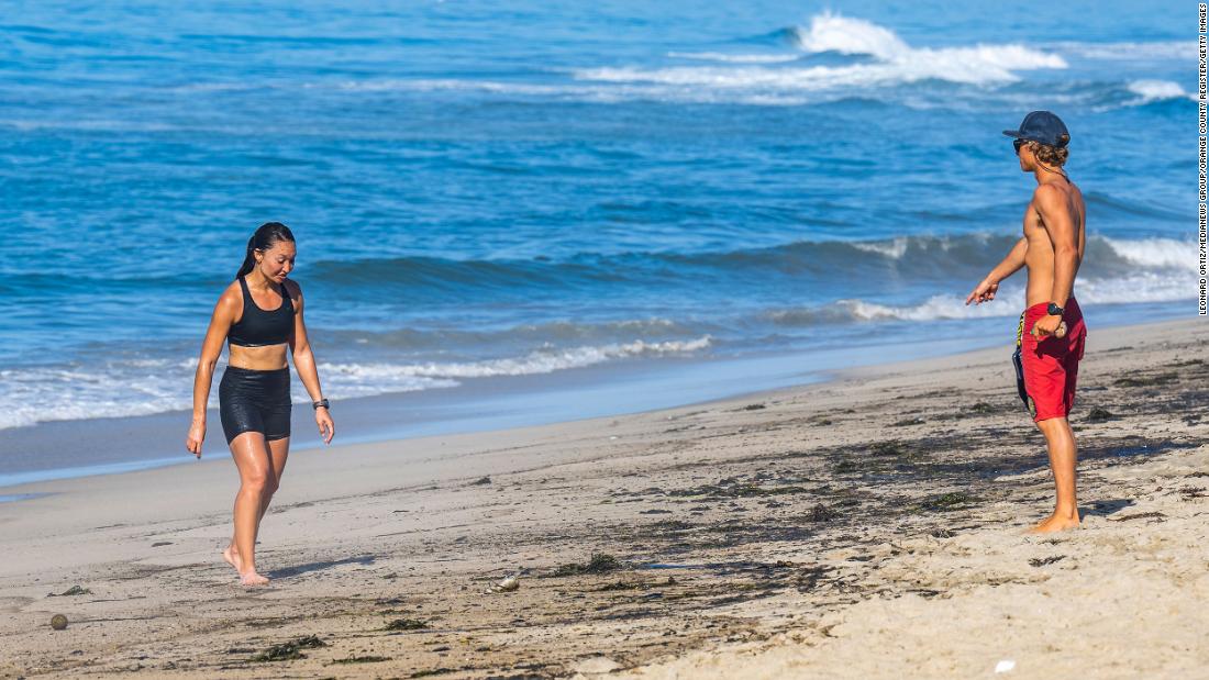 A Huntington Beach lifeguard points to the oil-soaked sand as he tells Melissa Panozzo to get out of the water on October 3. Panozzo hadn&#39;t heard the beaches had been closed, she said.