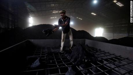 A laborer works inside a coal yard on the outskirts of Ahmedabad, India, in 2017.