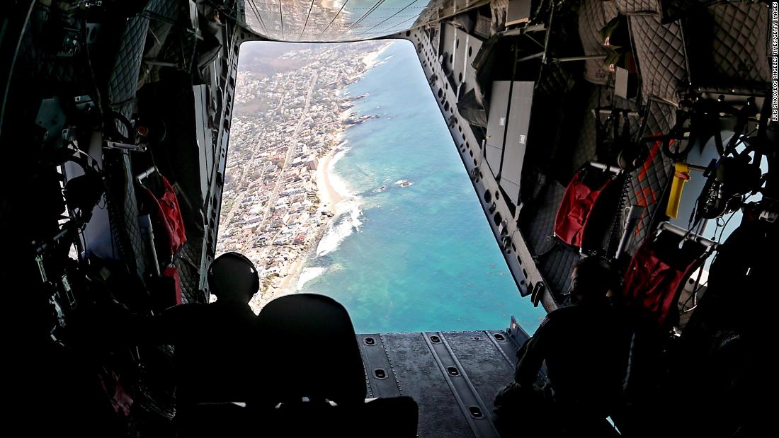 Members of a Coast Guard flight crew look out over the Orange County coastline as they search for oil in the water on Tuesday, October 5.