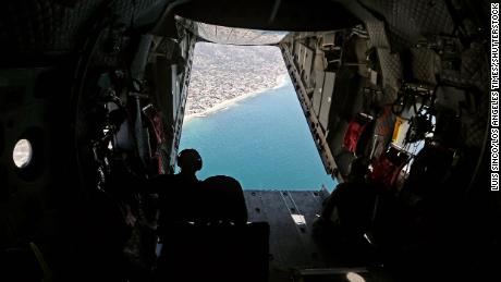 Members of a Coast Guard flight crew look out over the Orange County coastline as they search for oil in the water on October 5.