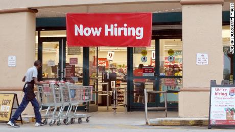 A Now Hiring sign hangs near the entrance to a Winn-Dixie Supermarket on September 21, 2021 in Hallandale, Florida. 