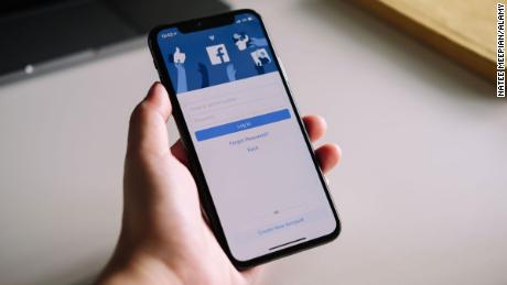 A woman&#39;s hand holding an iPhone X to use facebook with login screen. Facebook is a largest social network and most popular social networking site in the world.