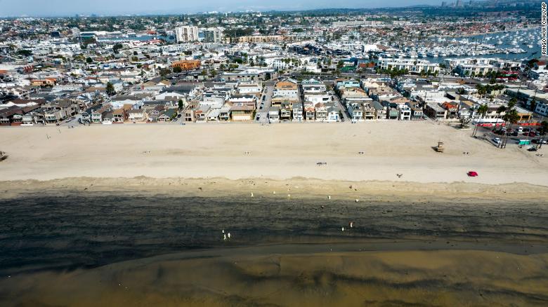 Workers in protective suits clean the contaminated beach after an oil spill in Newport Beach, California, on Wednesday, October 6, 2021.