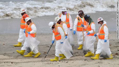 A cleanup crew works on the beach on Thursday, October 7, 2021 in Huntington Beach, California.