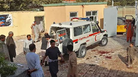 Afghan men stand next to an ambulance following an attack on a Shia mosque in Kunduz.