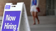 Pedestrians walk by a &quot;Now Hiring&quot; sign outside a store on August 16, 2021 in Arlington, Virginia. 