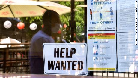 A &#39;Help Wanted&#39; sign is posted beside Coronavirus safety guidelines in front of a restaurant in Los Angeles, California on May 28, 2021. 