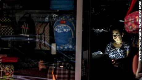 A Lebanese woman sits inside a suitcases shop during an electricity outage in September.