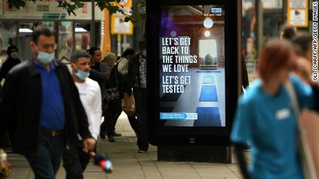 Pedestrians walk past an electronic display board promoting the &quot;Test and Trace&quot; coronavirus tracking scheme in Manchester, England, on August 3, 2020.