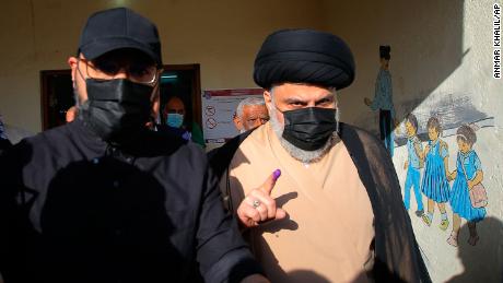 Populist Shia cleric Muqtada al-Sadr displays his ink-stained finger that shows he voted, at a polling center during the parliamentary elections in Najaf, Iraq, Sunday, Oct. 10, 2021.