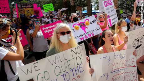 Participants wave signs as they walk back to Orlando City Hall during the March for Abortion Access on October 2.