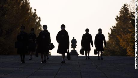 Japanese elementary school students dressed in traditional uniforms walk home after their lessons. 