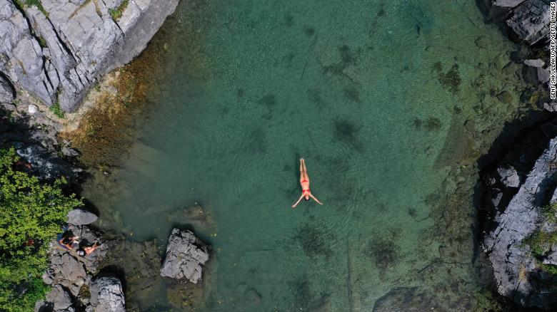 ผู้หญิงคนหนึ่งว่ายน้ำเพื่อคลายร้อนในทะเลสาบ Xhemas ทะเลสาบธรรมชาติขนาดเล็กที่ตั้งอยู่ในอุทยานแห่งชาติ Valbona ใกล้ Dragobi เมื่อวันที่ 4 สิงหาคม 2021