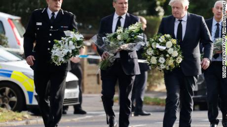 Britain&#39;s Prime Minister Boris Johnson (right), Britain&#39;s main opposition Labour Party leader Keir Starmer (center) and senior police officer Ben-Julian Harrington carry floral tributes to Belfairs Methodist Church in Leigh-on-Sea on Saturday.