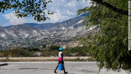 In this file image, a woman carries a bucket of water on the street in Croix des Bouquets, 8 miles northeast of the Haitian capital, Port-au-Prince, on December 30, 2019.